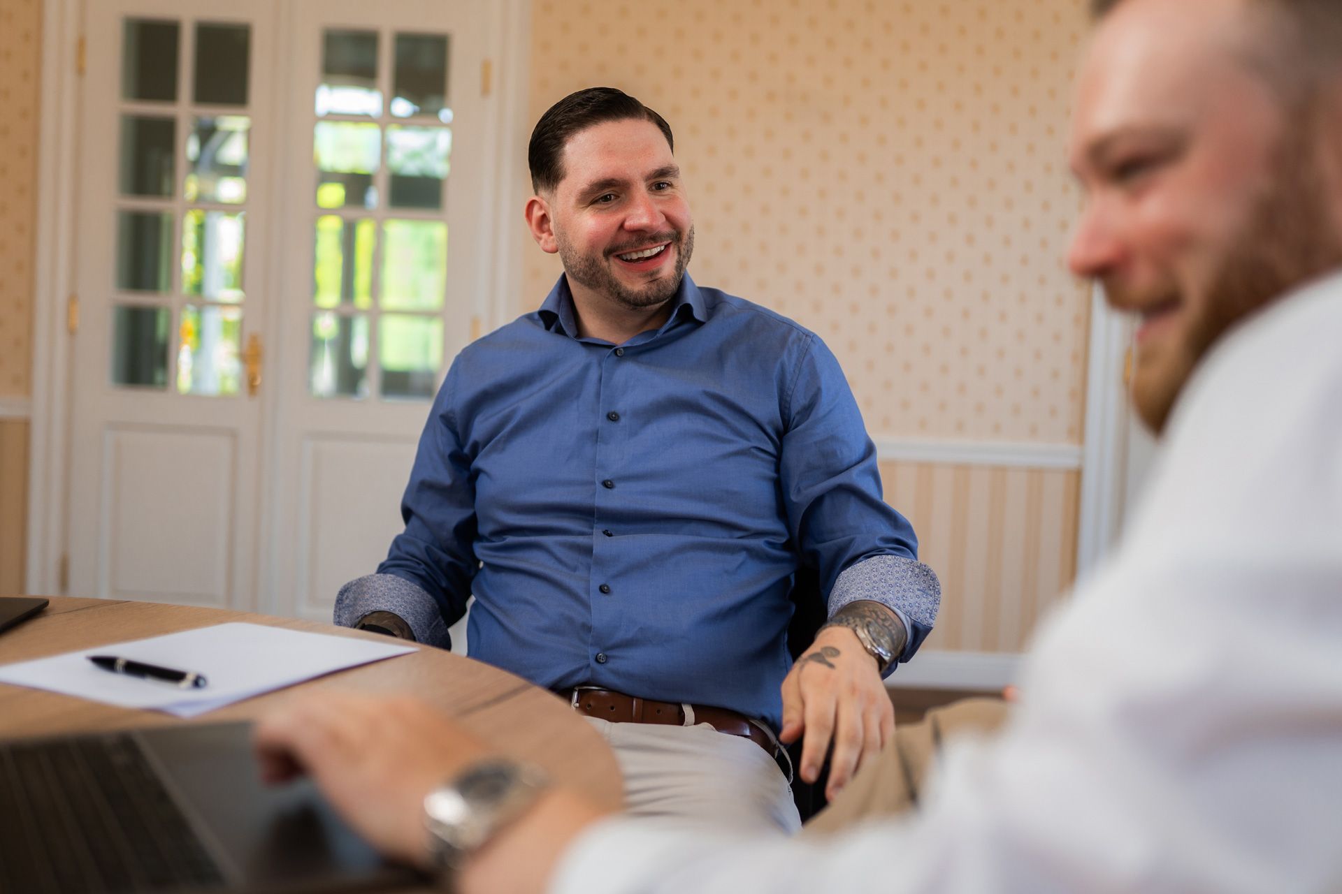 Zwei Männer führen ein entspanntes Gespräch in einem hellen Raum